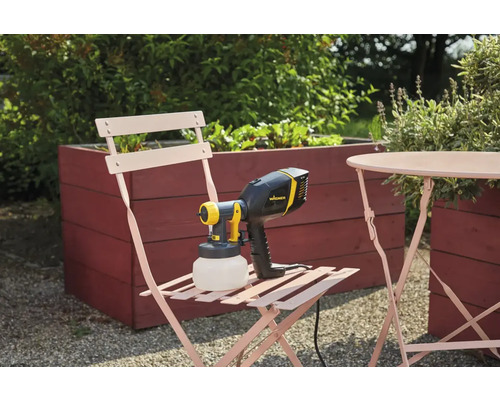 Système de pulvérisation de peinture Wagner sur une chaise de jardin à côté d''une table et d''un potager surélevé