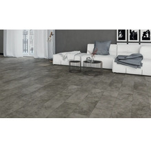 Salon avec carrelage de sol gris aspect pierre, canapé, table et fenêtre pour une ambiance claire et moderne.