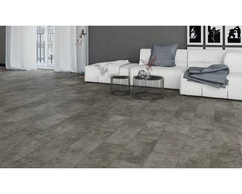 Salon avec carrelage de sol gris aspect pierre, canapé, table et fenêtre pour une ambiance claire et moderne.