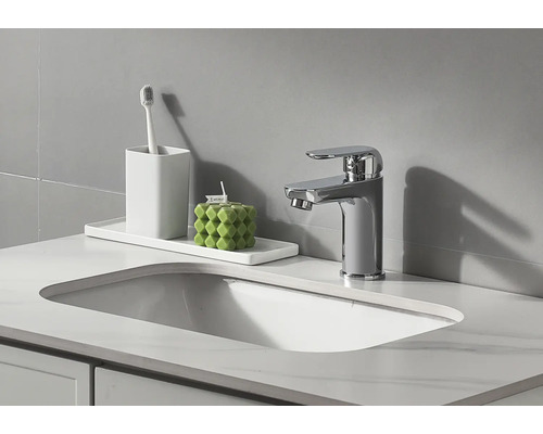 Badezimmer Waschbecken mit Armatur, Zahnputzbecher und dekorativer Kerze.