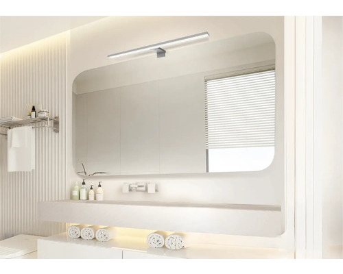 Salle de bain lumineuse avec miroir, lavabo et serviettes