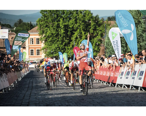 Cycliste célébrant sa victoire sur la ligne d''arrivée, entouré de spectateurs