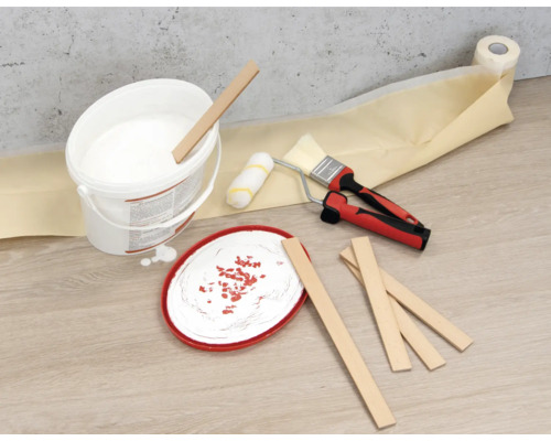 Seau de peinture, bâtons mélangeurs, rouleau à peinture, pinceau et ruban de masquage sur le sol