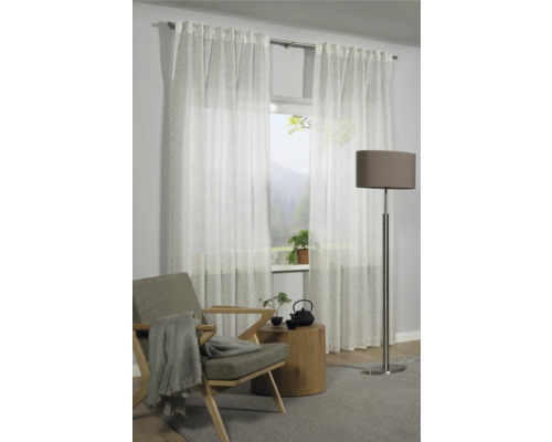 Wohnzimmer mit weißen, transparenten Gardinen, Sessel, Beistelltisch und Stehlampe.