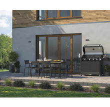 Terrasse avec barbecue, table et chaises devant une maison.