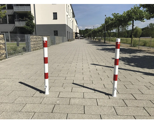 Deux bornes de délimitation à rayures rouges et blanches sur un chemin pavé.