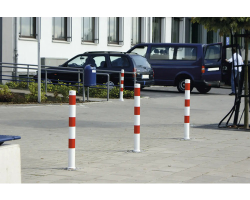 Plusieurs bornes de délimitation à rayures rouge et blanc sur un parking.