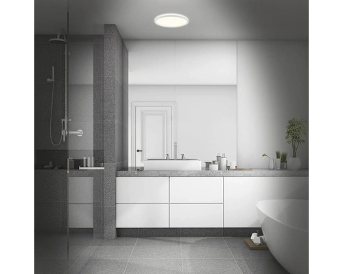 Salle de bains moderne avec douche, lavabo, miroir, baignoire et plafonnier rond.