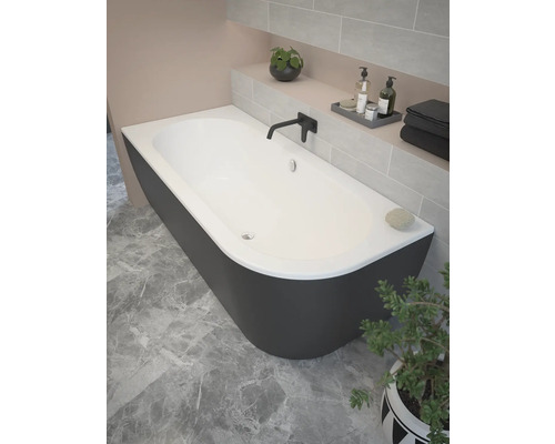 Freistehende Badewanne in einem Badezimmer mit Fliesenwand und Pflanze