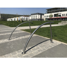 Deux supports à vélos incurvés en acier inoxydable sur une place pavée.