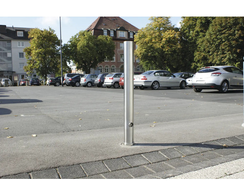 Borne en acier inoxydable sur un parking avec des voitures garées.