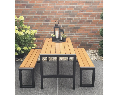 Table de jardin avec deux bancs devant un mur de briques