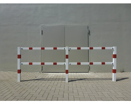 Barrière blanche et rouge devant un mur gris