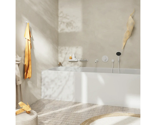 Salle de bains avec baignoire, serviette, peignoir et décorations dans un design clair.