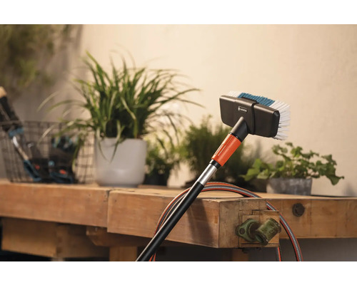 Brosse de lavage Gardena avec raccord d''eau devant des plantes sur un établi