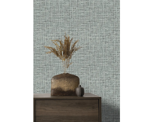 Nahaufnahme einer Wand mit Textiltapete, einem Sideboard und Vasen.