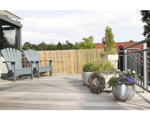 Terrasse avec deux chaises en bois, clôture en bambou et jardinières