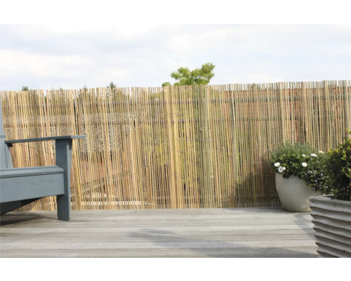 Clôture de confidentialité en bambou sur une terrasse avec terrasse en bois, à côté d''une chaise et de plantes en pot