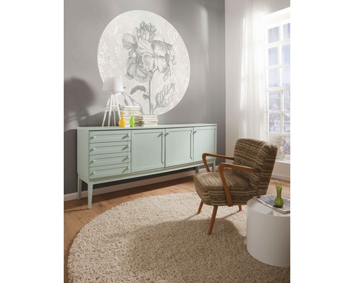 Wohnzimmer mit Kommode, Sessel, Teppich und Wanddekoration mit Blumenmuster