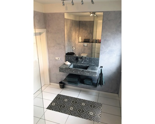 Salle de bain avec lavabo, miroir et tapis de bain à motifs