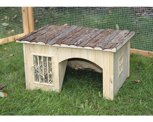 Kleintierhaus aus Holz mit Rinde auf dem Dach und Heu im Fenster