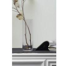 Branches décoratives dans un vase en verre et magazines sur une étagère