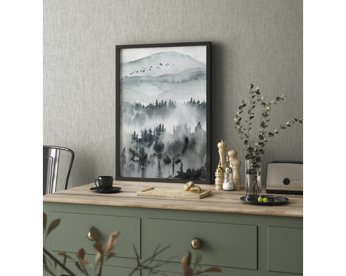 Dekoratives Gemälde mit Bergmotiv im Rahmen auf einem Küchentisch.