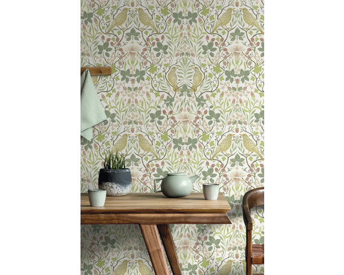 Wohnraum mit Mustertapete mit Vogel und Pflanzenmotiv hinter einem Holztisch