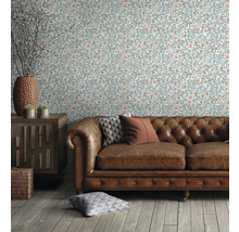 Salon avec papier peint à motifs floraux, canapé en cuir et meubles en bois pour une ambiance chaleureuse
