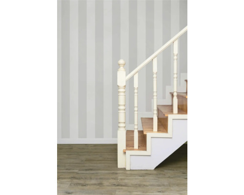 Escalier avec marches en bois et rampe blanche devant un mur rayé