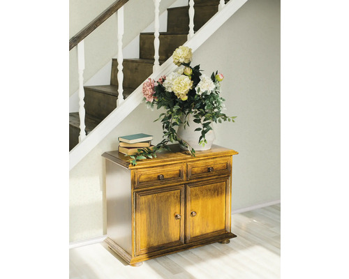 Szene mit Holzkommode, Büchern und Blumenstrauß unter einer Treppe