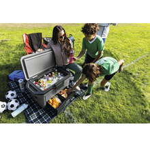 Szene im Freien mit Kühlbox, Getränken, Snacks und Kindern auf einem Rasenplatz.