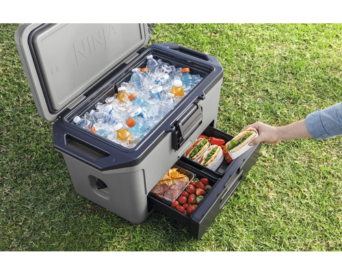 Geöffnete Kühlbox mit Eis, Getränken und ausziehbarer Schublade mit Lebensmitteln