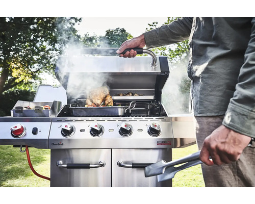 Edelstahl Grill mit Speisen und einer Person, die grillt