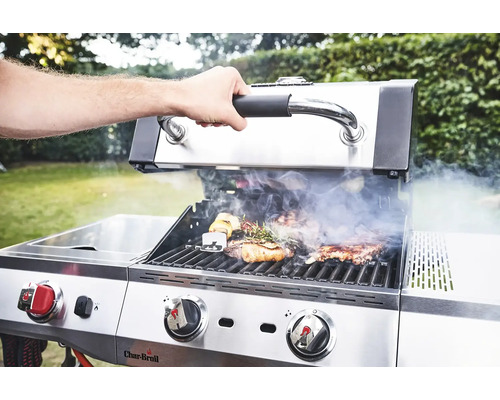 Un homme ouvre le couvercle d''un barbecue à gaz Char-Broil sur lequel se trouvent de la viande et des légumes.