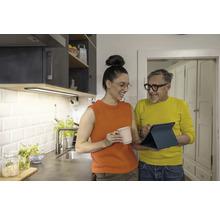 Helle Küche mit Unterbauleuchte, zwei Personen betrachten ein Tablet.