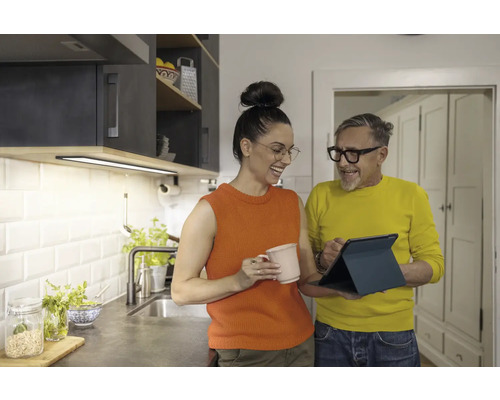 Helle Küche mit Unterbauleuchte, zwei Personen betrachten ein Tablet.