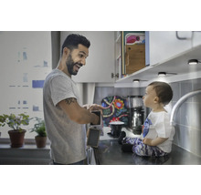 Vater zeigt Kind eine wiederaufladbare Leuchte in einer Küche mit Unterbaubeleuchtung.