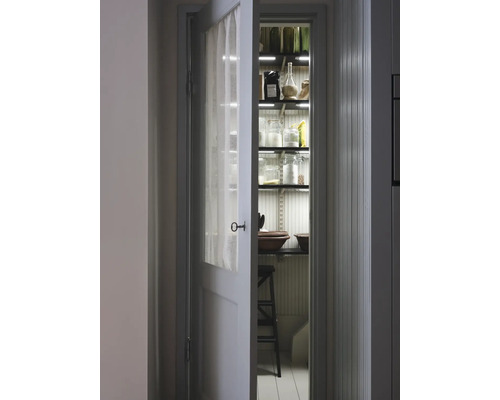 Porte de cellier ouverte avec étagères, bocaux en verre et éclairage