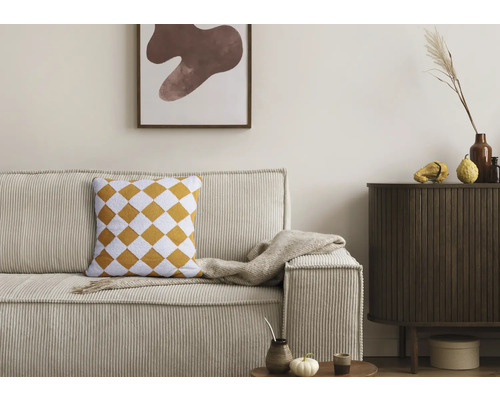 Salon avec canapé en velours côtelé, coussin à carreaux losanges et commode en bois