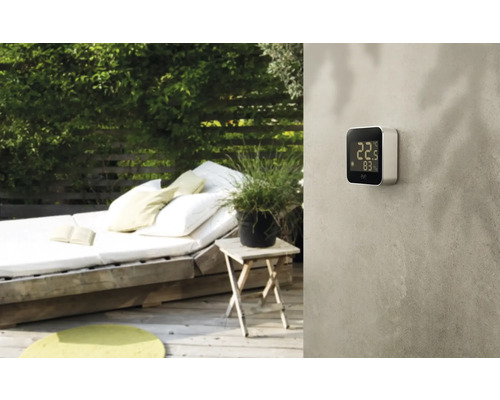 Scène de jardin avec thermomètre numérique au mur.
