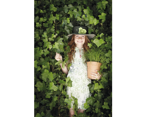 Mädchen mit Hut und Topfpflanze inmitten von Grünpflanzen