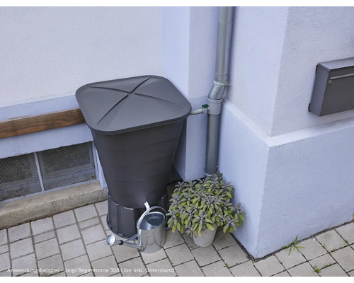 Récupérateur d''eau de pluie avec collecteur d''eau de pluie, arrosoir et plantation devant un mur de maison