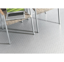 Revêtement de sol clair avec motif de tôle gaufrée sous une chaise et un ordinateur portable.