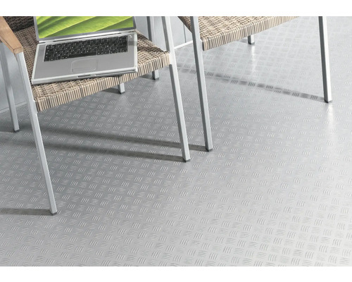 Revêtement de sol clair avec motif de tôle gaufrée sous une chaise et un ordinateur portable.