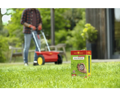 Paquet de regarnissage turbo Wolf Garten devant un homme avec un épandeur sur une pelouse
