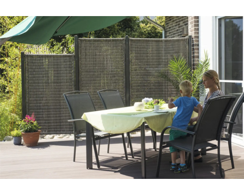 Sichtschutzzaun aus Kunststoffgeflecht und Gartentisch mit Stühlen auf einer Terrasse