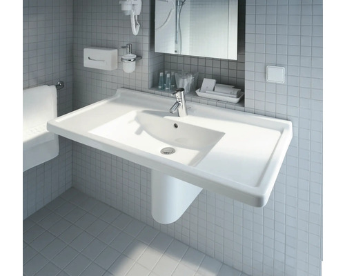 Weißes Waschbecken mit Armatur im Badezimmer vor Fliesenwand.