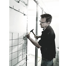 Un homme utilise un marteau et un burin pour retirer des carreaux d''un mur.