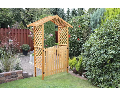 Vue de jardin avec portail en bois et arche à roses dans le jardin